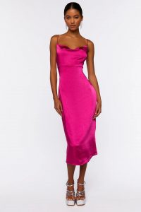 A woman posing in a hot pink satin slip dress