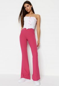 A woman posing donning a hot pink flared pants and white top