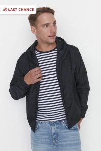 a man posing in navy blue hoodie and jeans