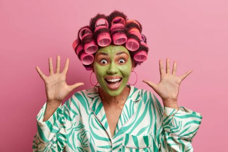 Girl with hair curlers with green face mask