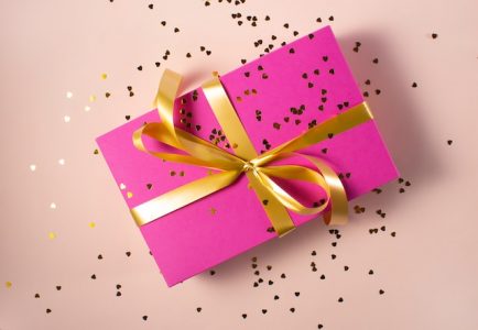Gift box wrapped with pink wrapper and golden tape